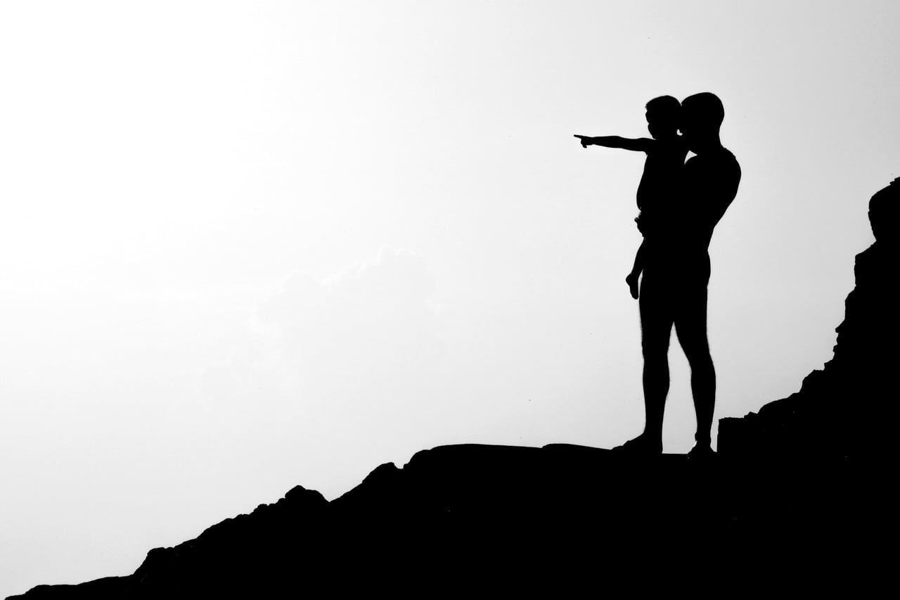 Silhouette d'un parent et d'un enfant à contre-jour, moment de complicité.