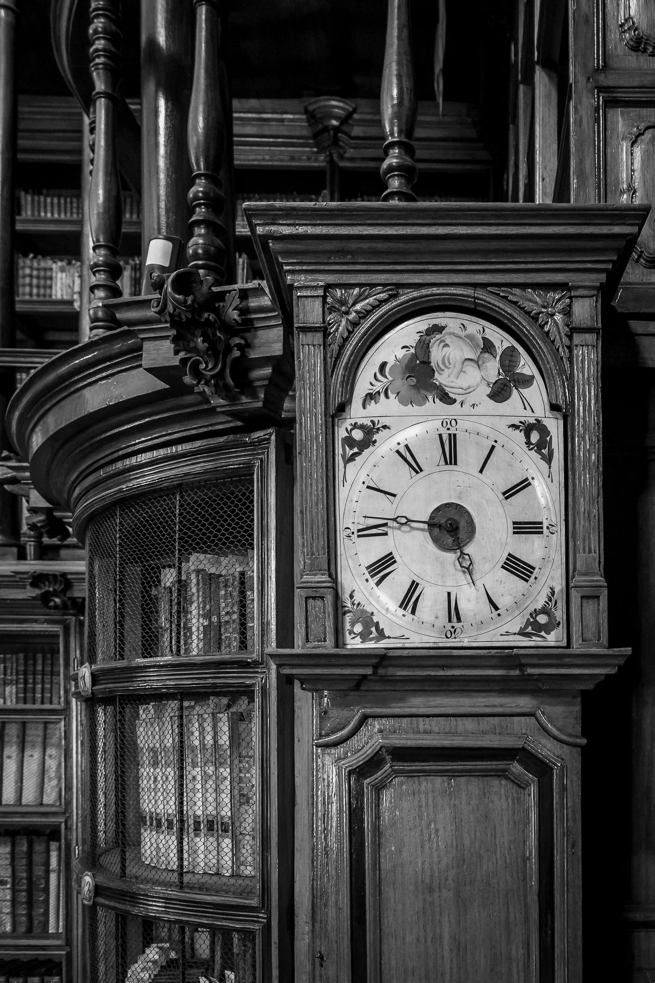 Horloge ancienne devant une bibliothèque de livres reliés.